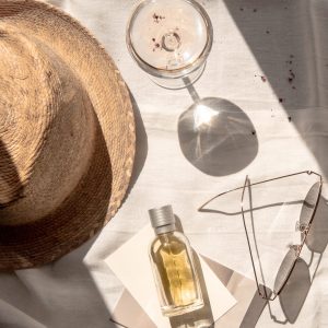 flay lay of sun hat, cocktail, perfume and sunglasses