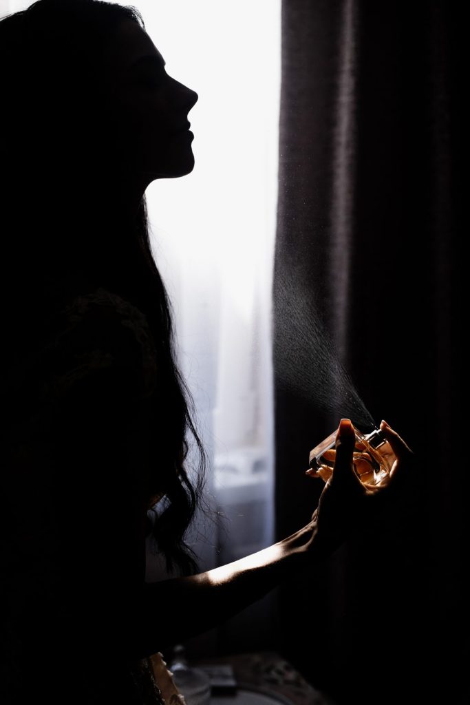 Silhouette of a woman in the dark spraying perfume