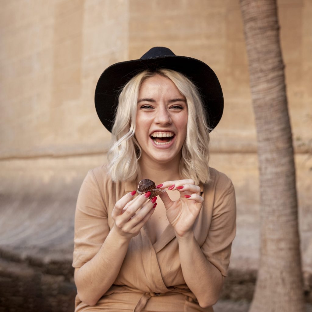 blonde woman wearing a hat and eating a cake