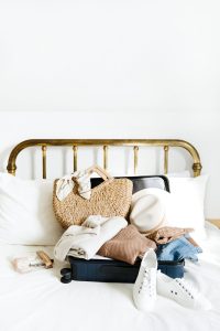 open luggage on bed fulled with summer clothing