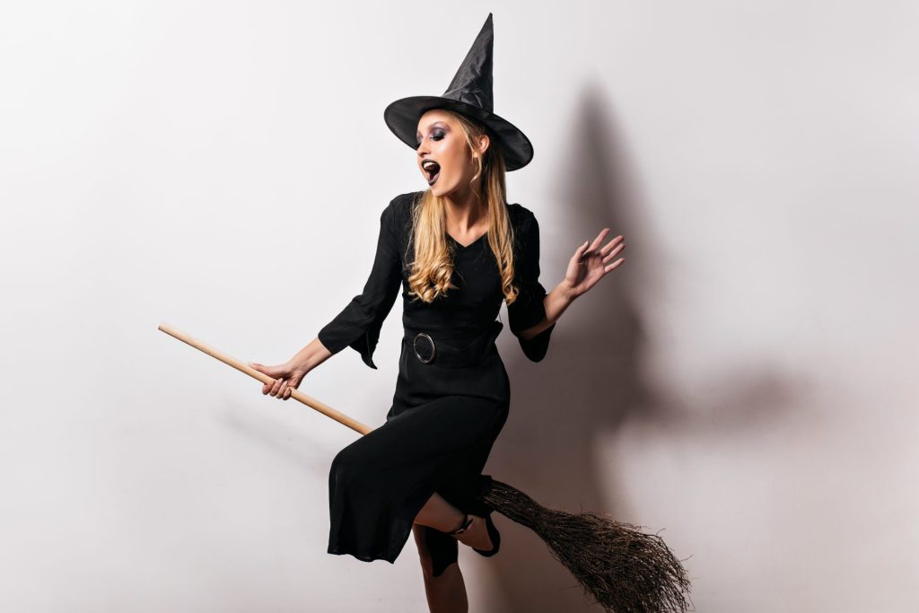 happy blonde woman dressed up as a witch on a broom